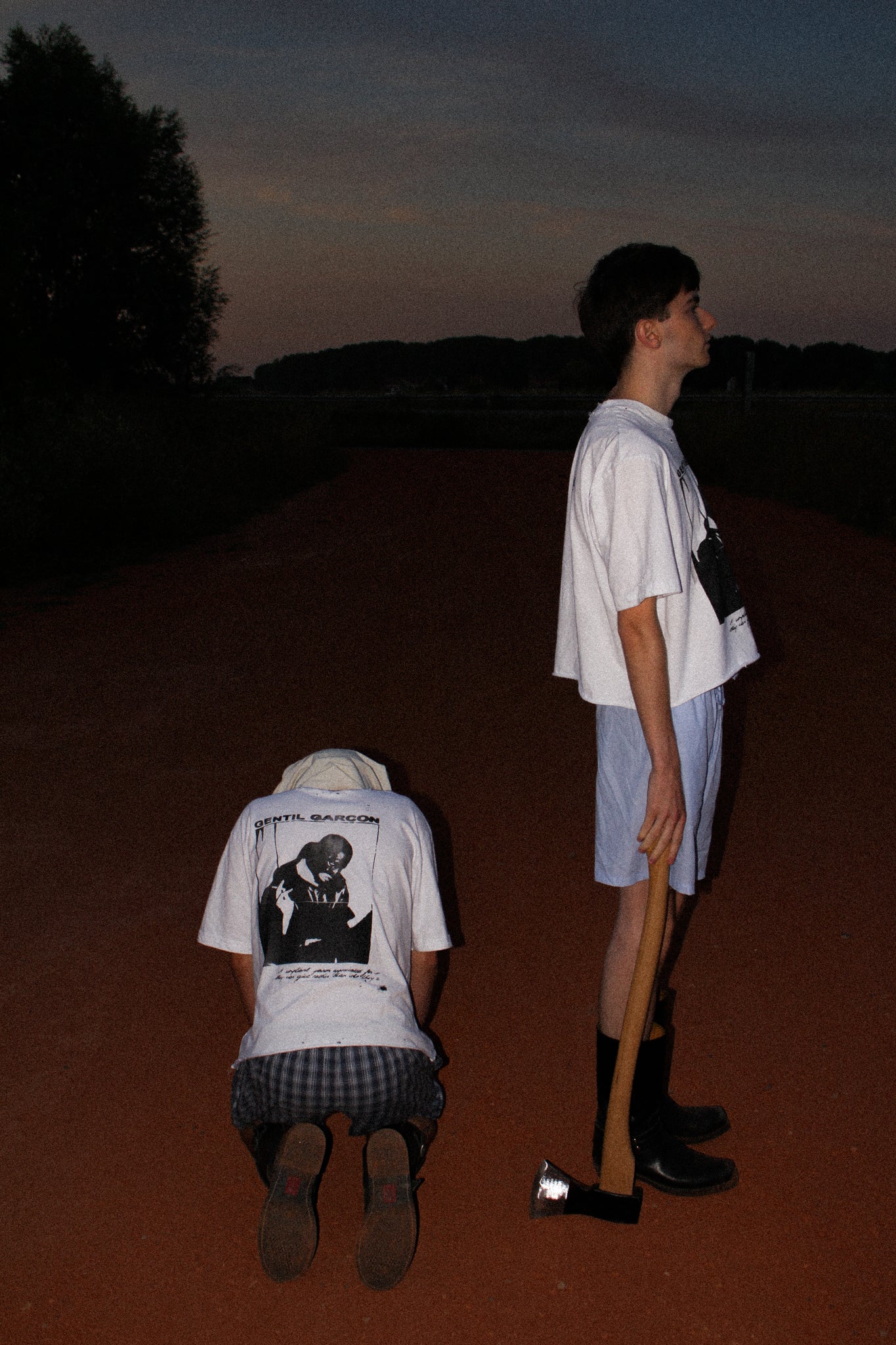 WHITE OVERSIZED GENTIL GARÇON GRAPHIC T-SHIRT FEATURING A FRONT AND BACK PRINT, SHOWN IN AN EDITORIAL CAMPAIGN WITH TWO MODELS IN A NIGHTTIME OUTDOOR SETTING.