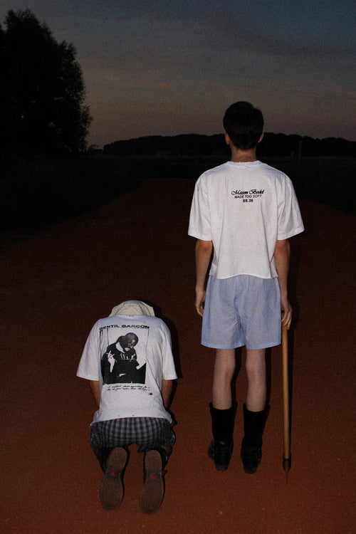 WHITE OVERSIZED GENTIL GARÇON GRAPHIC T-SHIRT FEATURING A FRONT AND BACK PRINT, SHOWN IN AN EDITORIAL CAMPAIGN WITH TWO MODELS IN A NIGHTTIME OUTDOOR SETTING.